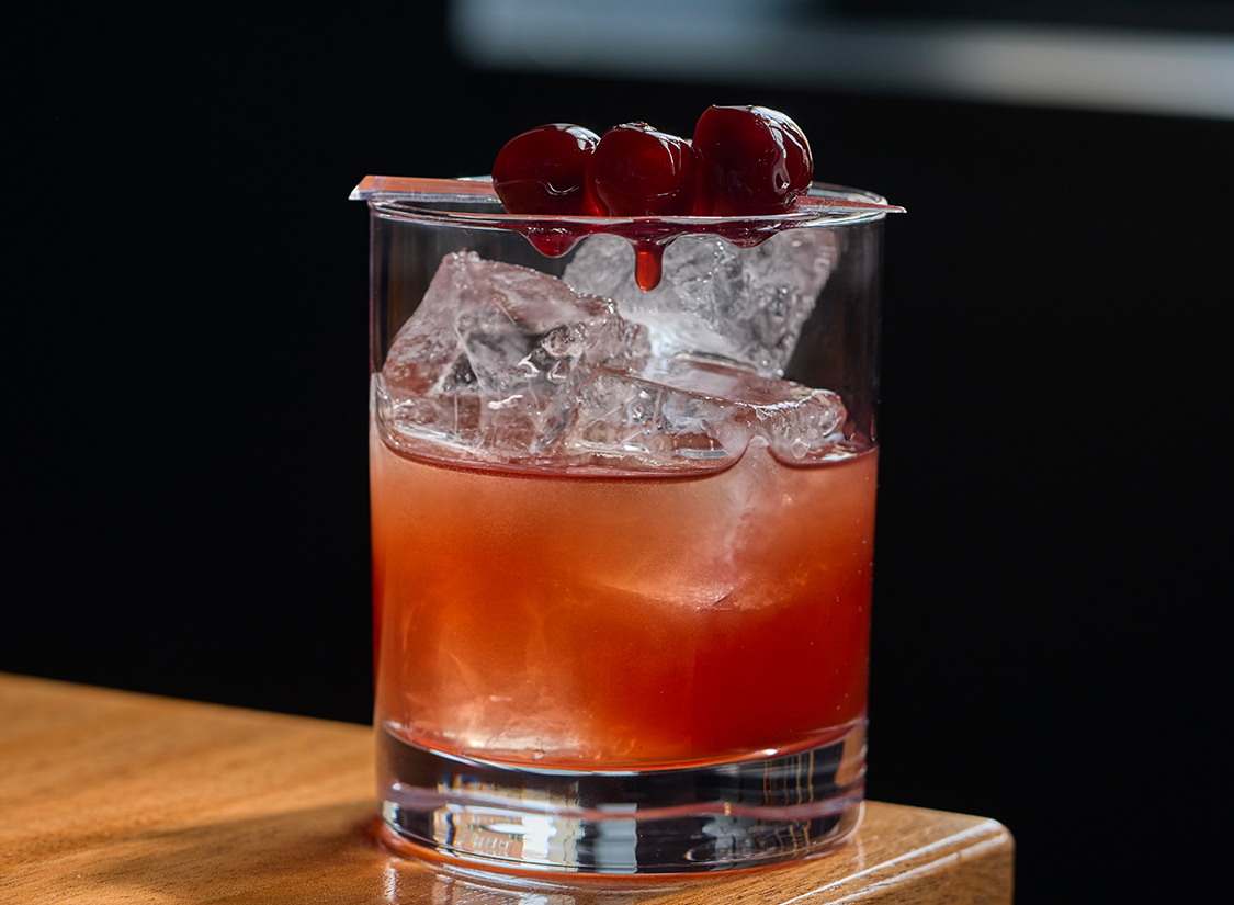 a glass with a drink and cherries on top